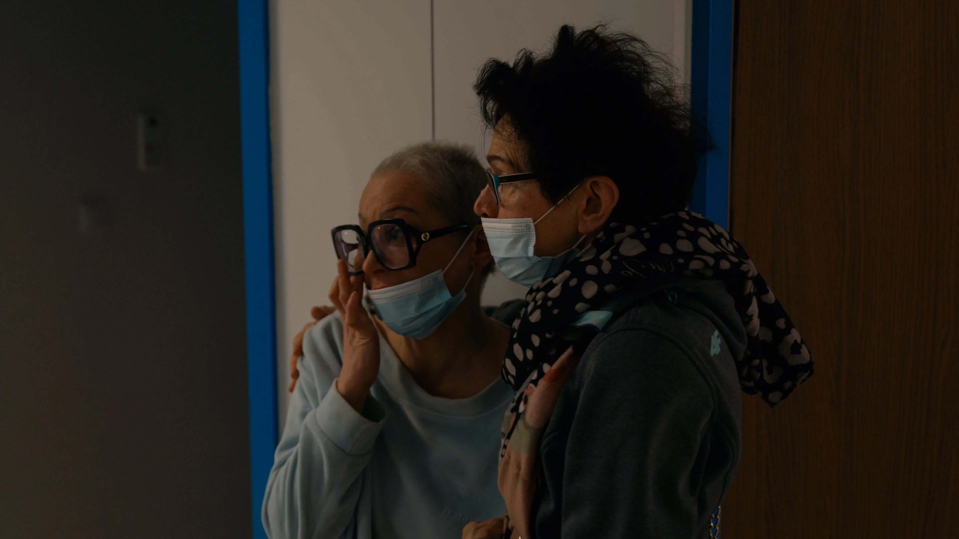 Two women with glasses and masks looking to the left